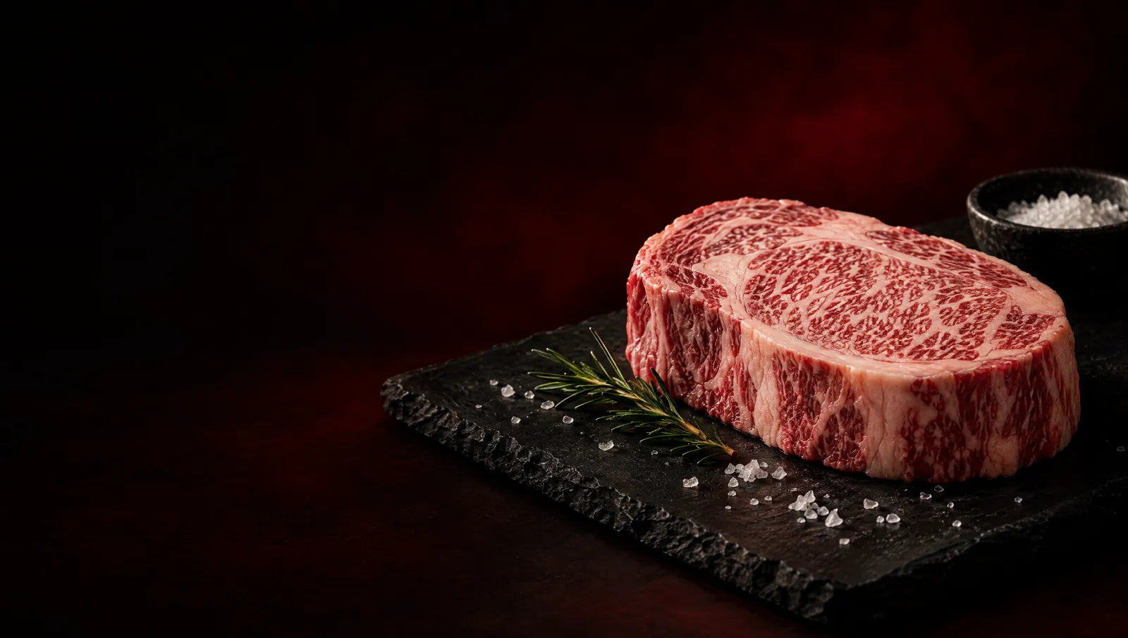 Raw Japanese A5 Wagyu ribeye with fine white marbling on a black slate board